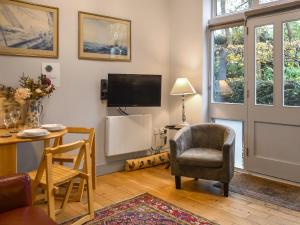 a living room with a tv and a chair and a table at The Coach House - Uk50884 in North Walsham