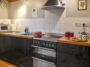 a kitchen with a stove and a sink at The Coach House - Uk50884 in North Walsham