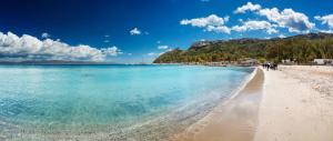 a beach with people walking on the sand and the water at "Da Carla e Sandro"- Appartamento con parcheggio privato in Quartucciu