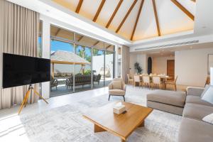 a living room with a large television and a dining room at Anchan Flora by Villacarte in Ban Phru Champa