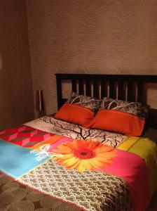 a bed with a colorful comforter with a flower on it at COMME chez VOUS in Saint-Satur