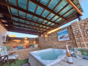a hot tub in a patio with a wooden roof at Windsong Living - Eagle Owl in Krugersdorp