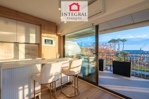 a kitchen with a bar with white chairs and a balcony at Les Palmeres Palamós in Palamós