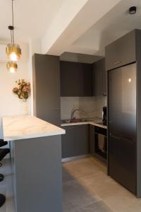 a kitchen with black cabinets and a white counter top at Signature city loft in Tríkala