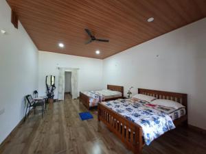 a bedroom with two beds and a ceiling fan at Whispering Meadows By Dazzle Destinations - Coorg in Somvārpet