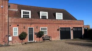 a brick building with two doors and a bench in front at The Coach House WPH, Epping in Epping