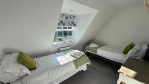 two beds in a small room with a window at The Coach House WPH, Epping in Epping