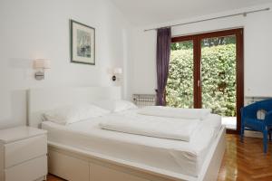 a white bedroom with a bed and a window at Apartmani Alice in Njivice