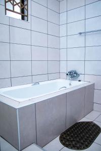 a bath tub in a white tiled bathroom at The River Boutique Inn in Lobamba +100 photos