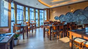 a restaurant with wooden tables and chairs and windows at Yashshree Jai Hotel & Banquet in Darjeeling