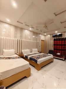 a bedroom with two beds and a tv on the wall at Glorious Guest House & Hotel in Multan