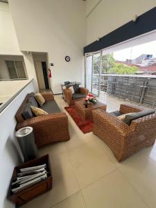 a living room with wicker furniture and a large window at Suite de hotel dentro centro comercial in Cartago