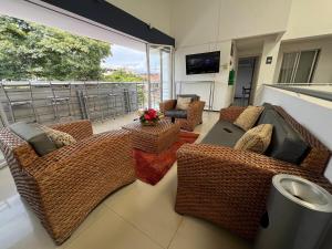 a living room with wicker furniture and a large window at Suite de hotel dentro centro comercial in Cartago