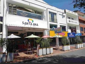 a building with tables and umbrellas on a street at Suite de hotel dentro centro comercial in Cartago +14 photos