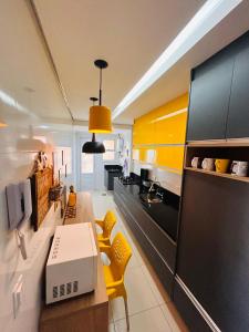a kitchen with yellow cabinets and a table with a laptop at Ilha Salinas Canto do Forte in Praia Grande