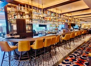 a bar with yellow bar stools in a restaurant at The Crescat Suite by Cinnamon Grand in Colombo