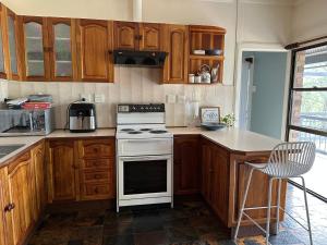 a kitchen with wooden cabinets and a white stove top oven at The Haven House in Singleton