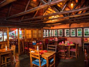 a restaurant with wooden tables and chairs and windows at Malandela's Guest House in Malkerns