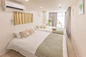 two beds in a room with white walls at night-night 東京ドーム便利 江戸川橋駅近 池袋銀座直通 商店街徒歩圏内 in Tokyo