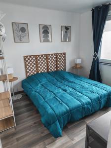 a bed in a bedroom with a blue comforter at Appart 1 bray dunes Minouche in Bray-Dunes
