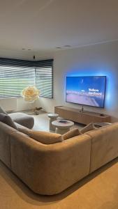 a living room with a large couch and a flat screen tv at Inspire Residence and private Wellness in Tongeren