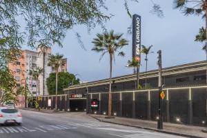 a car driving past a building with palm trees at Spa urbano Motel Adult Only in Fortaleza