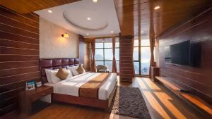 a bedroom with a bed and a flat screen tv at Yashshree Jai Hotel & Banquet in Darjeeling