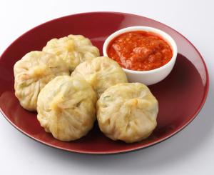 a red plate with dumplings and a bowl of sauce at Karma homestay in Ravangla +9 photos