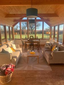 a living room with couches and a table and windows at Auchencairn Cottage in Brora