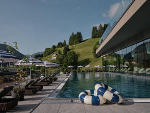 a swimming pool with lounge chairs and umbrellas at a resort at DAS EDELWEISS - Salzburg Mountain Resort in Grossarl