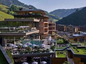a building with a pool and chairs and umbrellas at DAS EDELWEISS - Salzburg Mountain Resort in Grossarl
