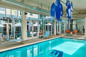 a pool with blue chairs and umbrellas in a building at Aloft by Marriott Austin Northwest in Austin