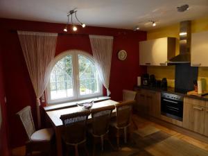 a kitchen with a table with chairs and a window at Villa Edelstein in Mörschied