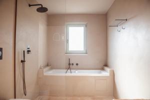 a bathroom with a bath tub and a window at Dimora Stune in Ostuni