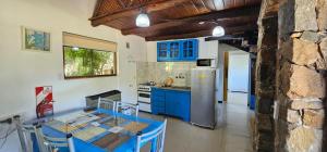 a kitchen with blue cabinets and a table and a kitchen with a refrigerator at Amanecer en las Piedras in Tandil
