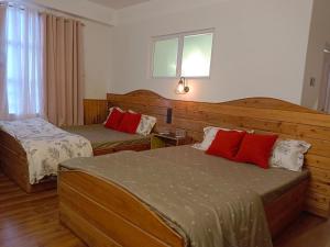 a hotel room with two beds with red pillows at Ratnagiri Boutique Hotel in Mirik +29 photos