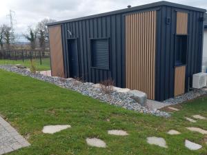 a black building with two doors and a grass field at Maison studio de jardin in Naucelles