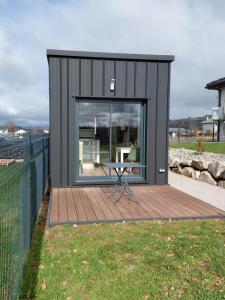 a black tiny house with a table on a deck at Maison studio de jardin in Naucelles