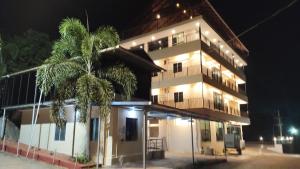 a tall building with a palm tree in front of it at Sansav Garden Resort in Gurpur