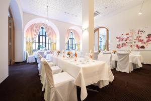 a room with white tables with white chairs and windows at Hotel VICTORIA Nürnberg in Nuremberg