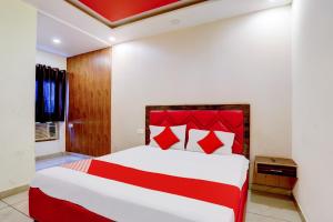 a bedroom with a red and white bed in a room at Hotel O Elibrista in Meerut +29 photos