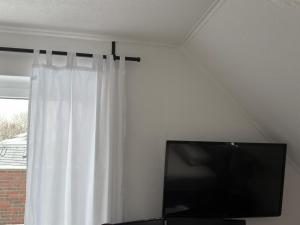 a flat screen tv sitting next to a window at Quendel & Äpfel Ferienhaus in Neu Wulmstorf