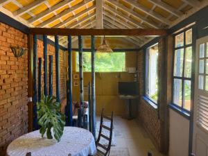 a dining room with a table and chairs and windows at Casinha Rústica de Paty in Paty do Alferes