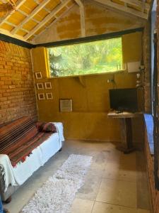 a room with a bed and a desk and a window at Casinha Rústica de Paty in Paty do Alferes