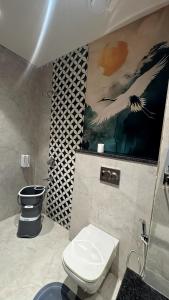 a bathroom with a toilet and a painting on the wall at Hotel The Grand Mirage in Bathinda