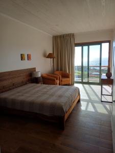 a bedroom with a bed and a chair and a window at Salga Lodge in Angra do Heroísmo