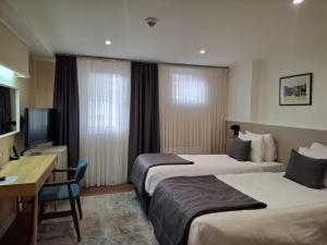 a hotel room with two beds and a desk at Hotel Astra in Sarajevo +98 photos