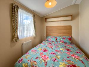 a bedroom with a bed with a floral bedspread at Peppy in Newton Stewart