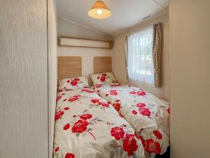 a bedroom with a bed with red flowers on it at Peppy in Newton Stewart