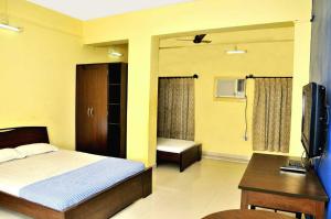 a bedroom with a bed and a desk and a television at Bothra Guest House in Kolkata